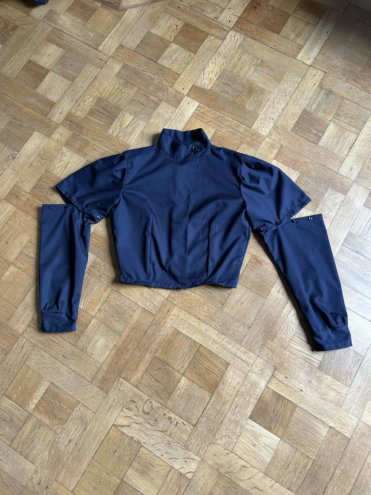 Navy detachable long sleeves with short-sleeve top component of modular dress arranged on wooden floor